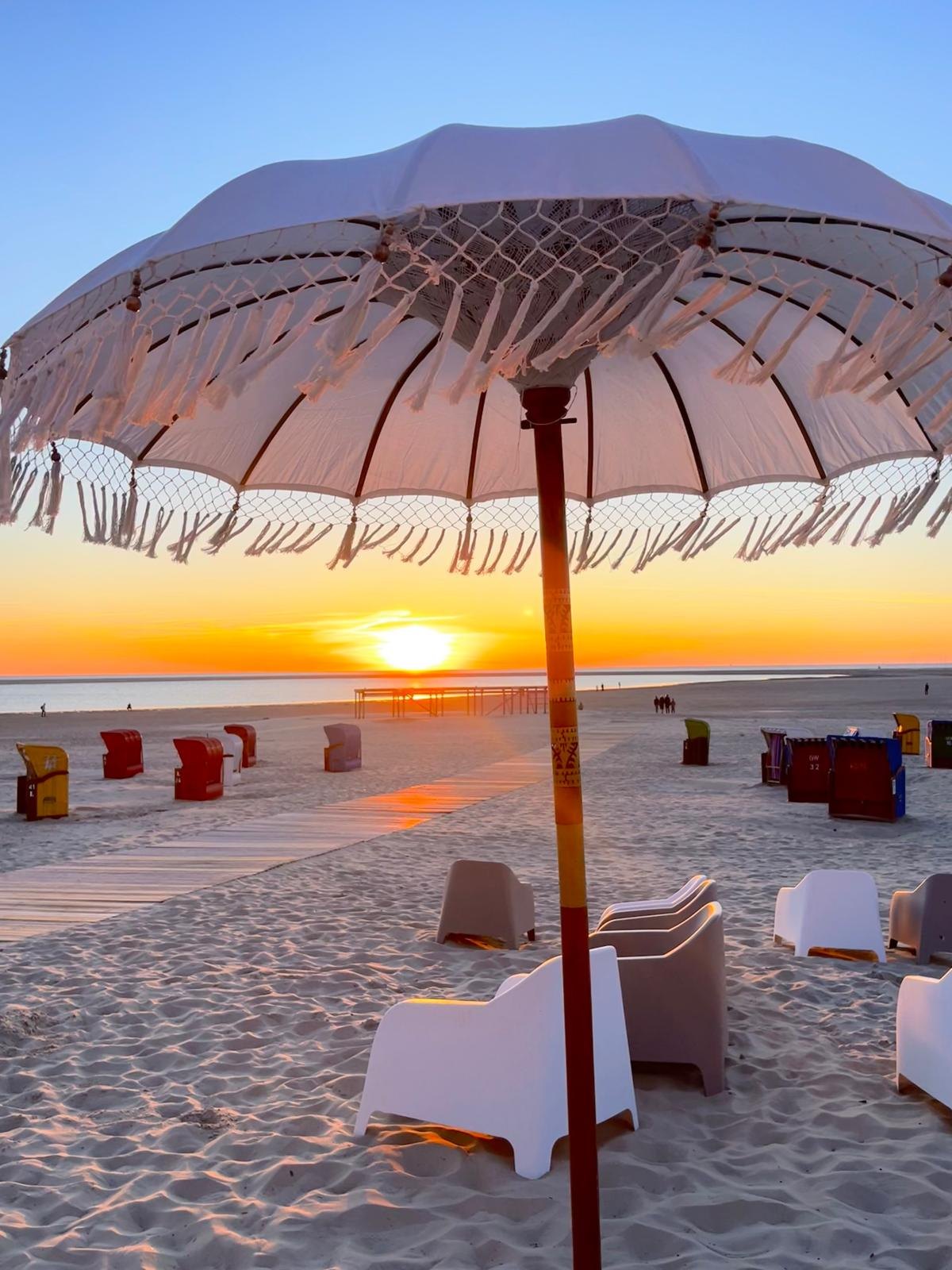 Sonnenuntergang am Strand mit Sonnenschirm und Strandkörben