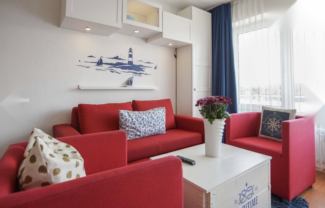 Wohnzimmer mit rotem Sofa und maritimen Akzenten