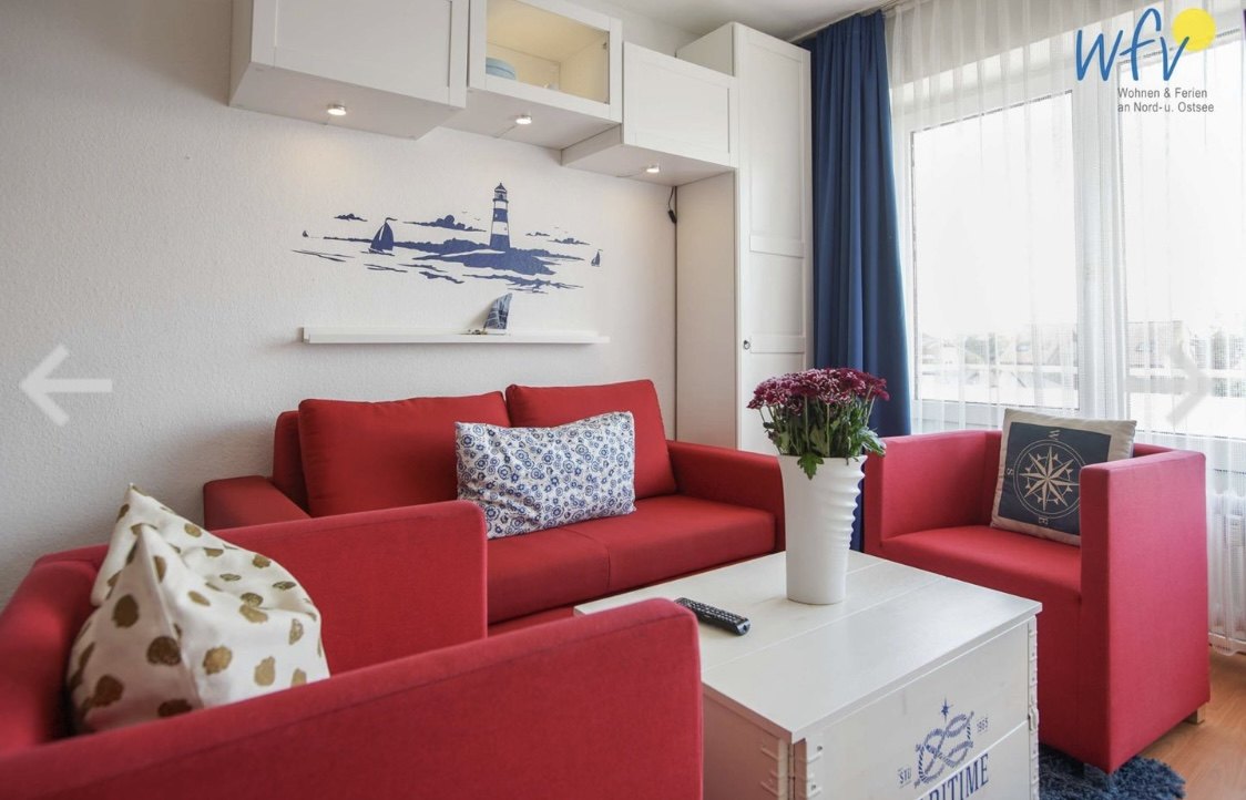 Wohnzimmer mit rotem Sofa und maritimen Akzenten